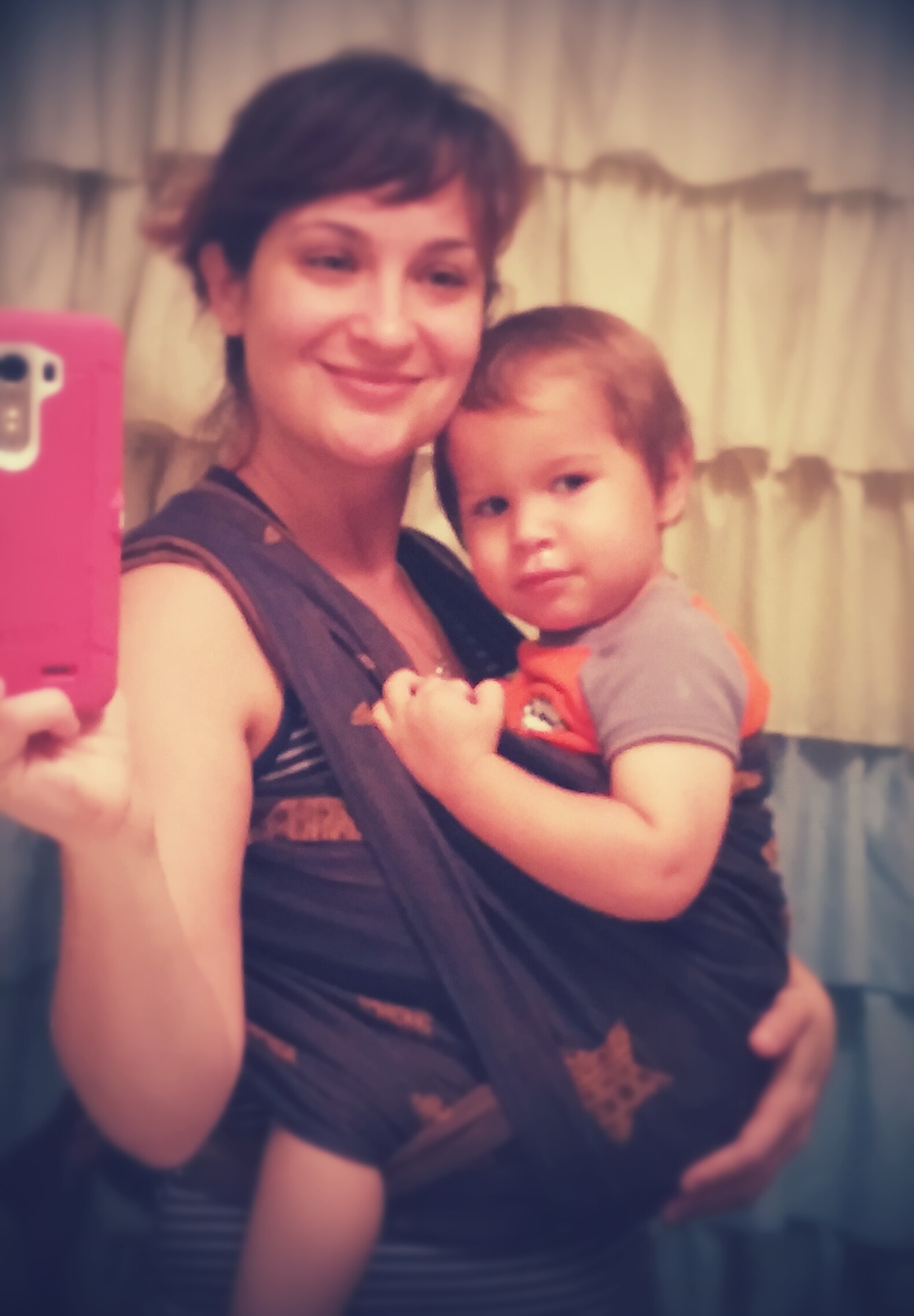A mother holding her toddler close in a carrier