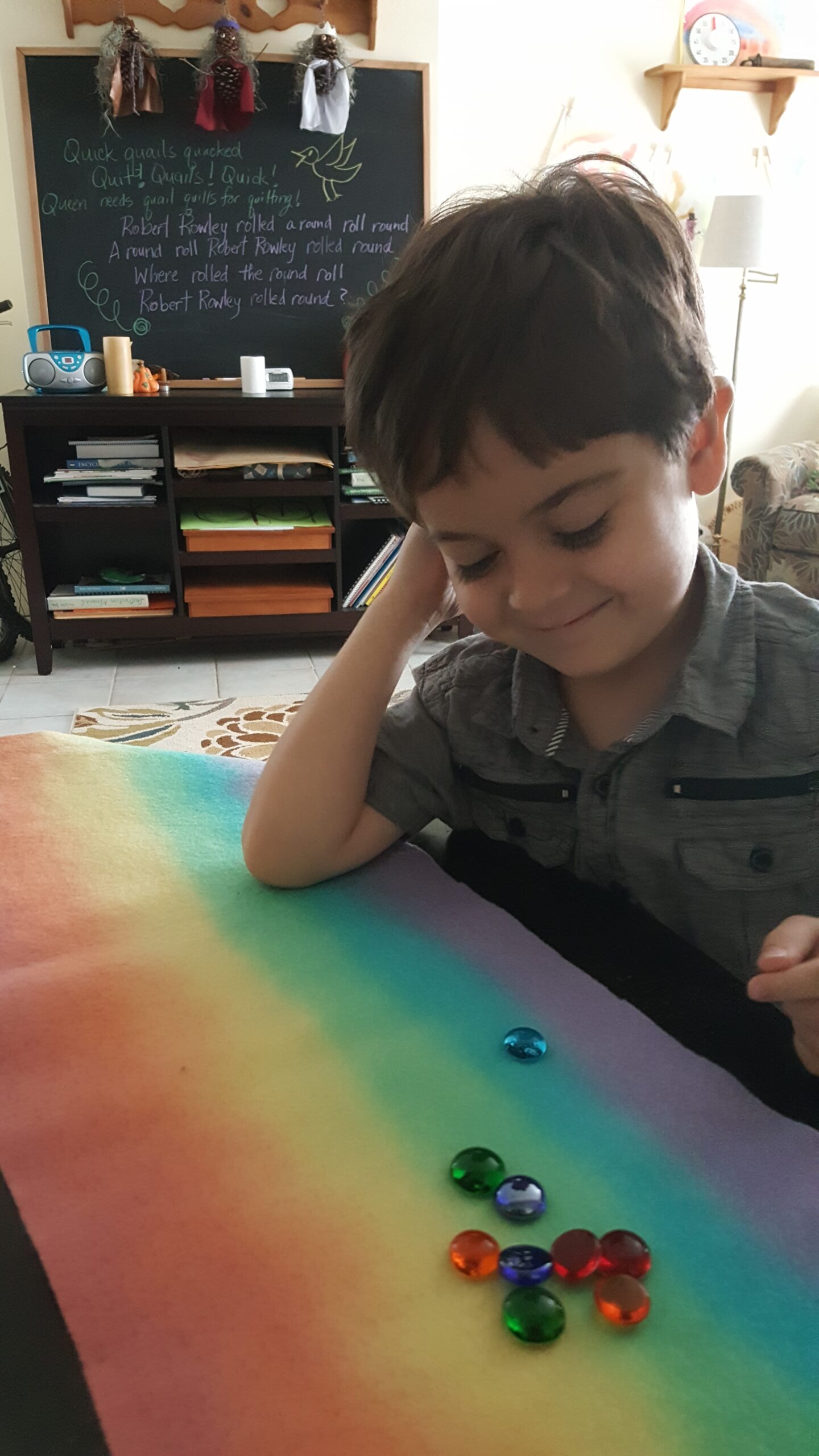 A small boy smiling beside a rainbow play silk