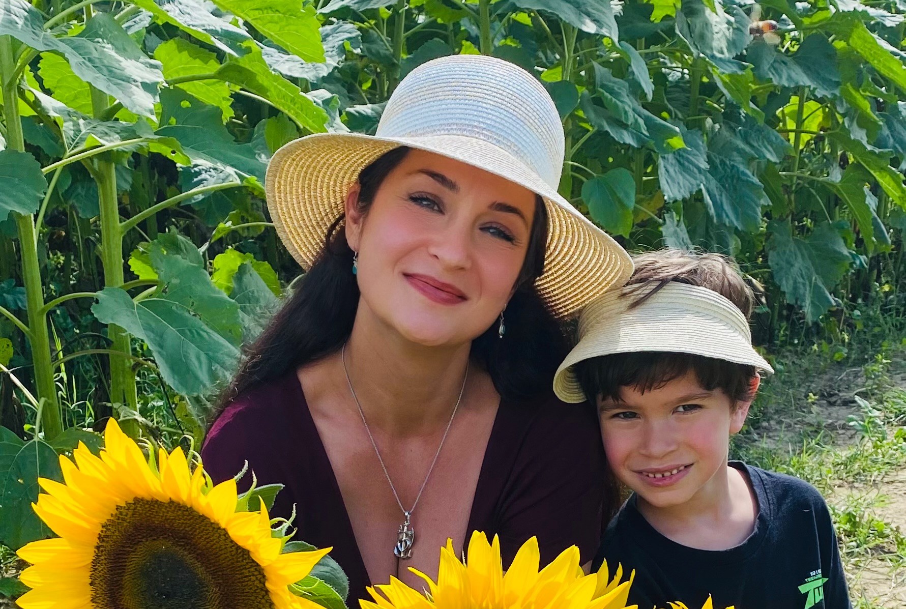 Melanie and her son smiling among tall sunflowers