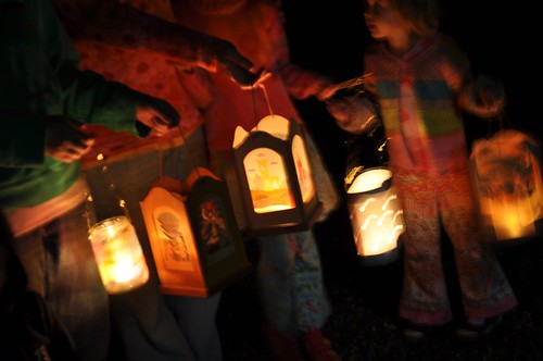 Children carrying glowing handmade lanterns in the dark