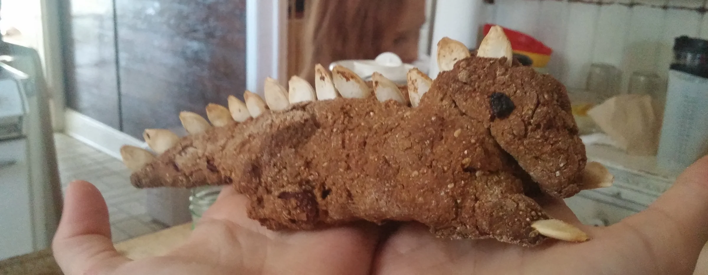 A child’s hands holding a dragon bread baked for Michaelmas, almond scales along its back