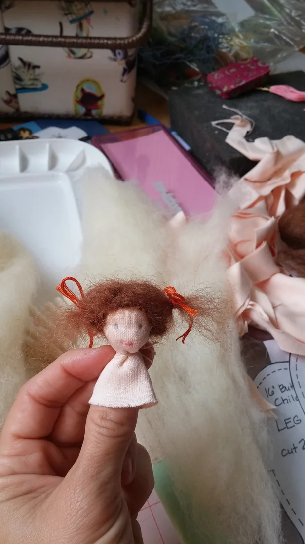 A small cloth doll being made, held between finger and thumb