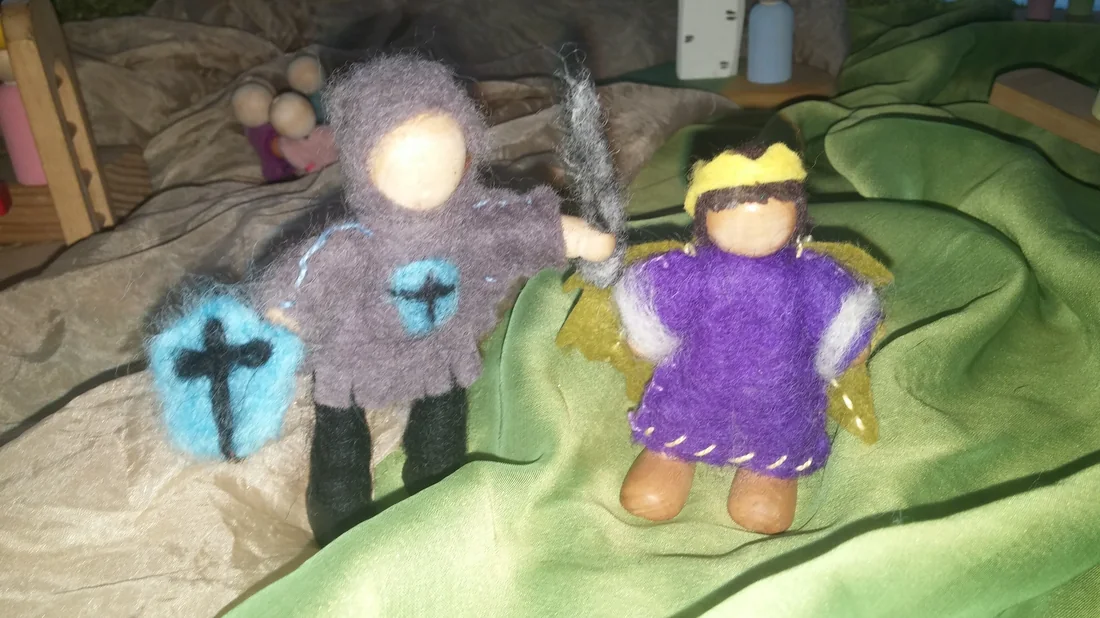 Two small felted figures, a knight and an angel, on a green silk