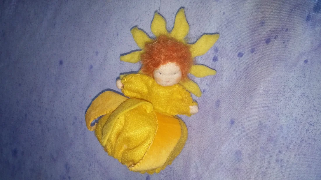 A small felted doll dressed as a sunflower