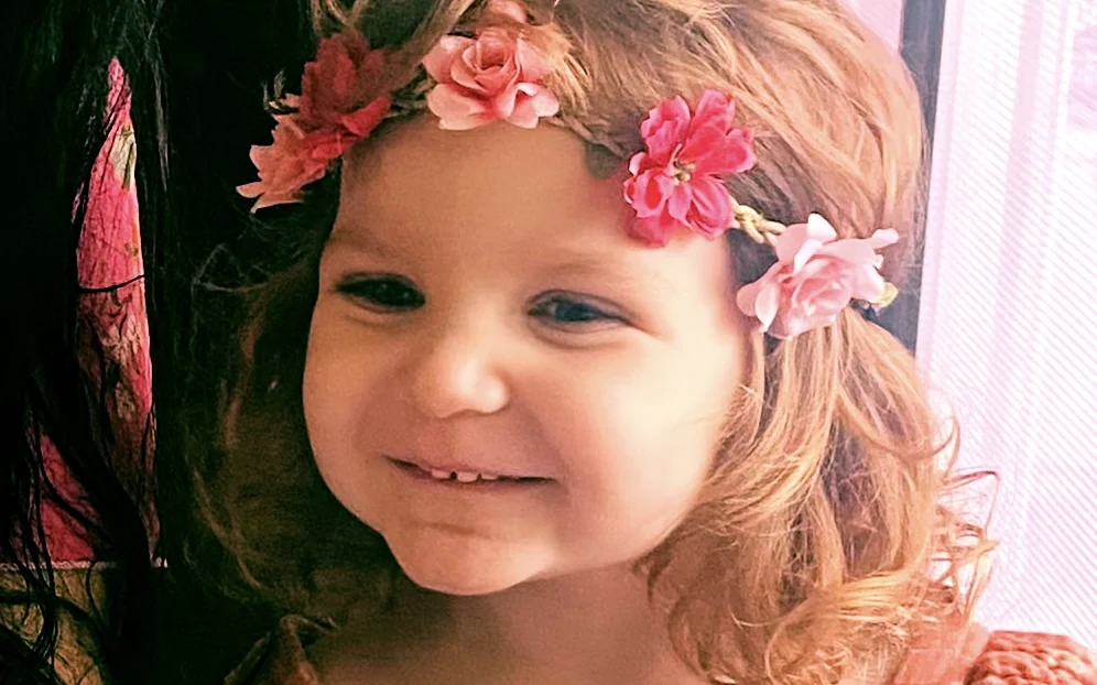 A young child wearing a crown of flowers